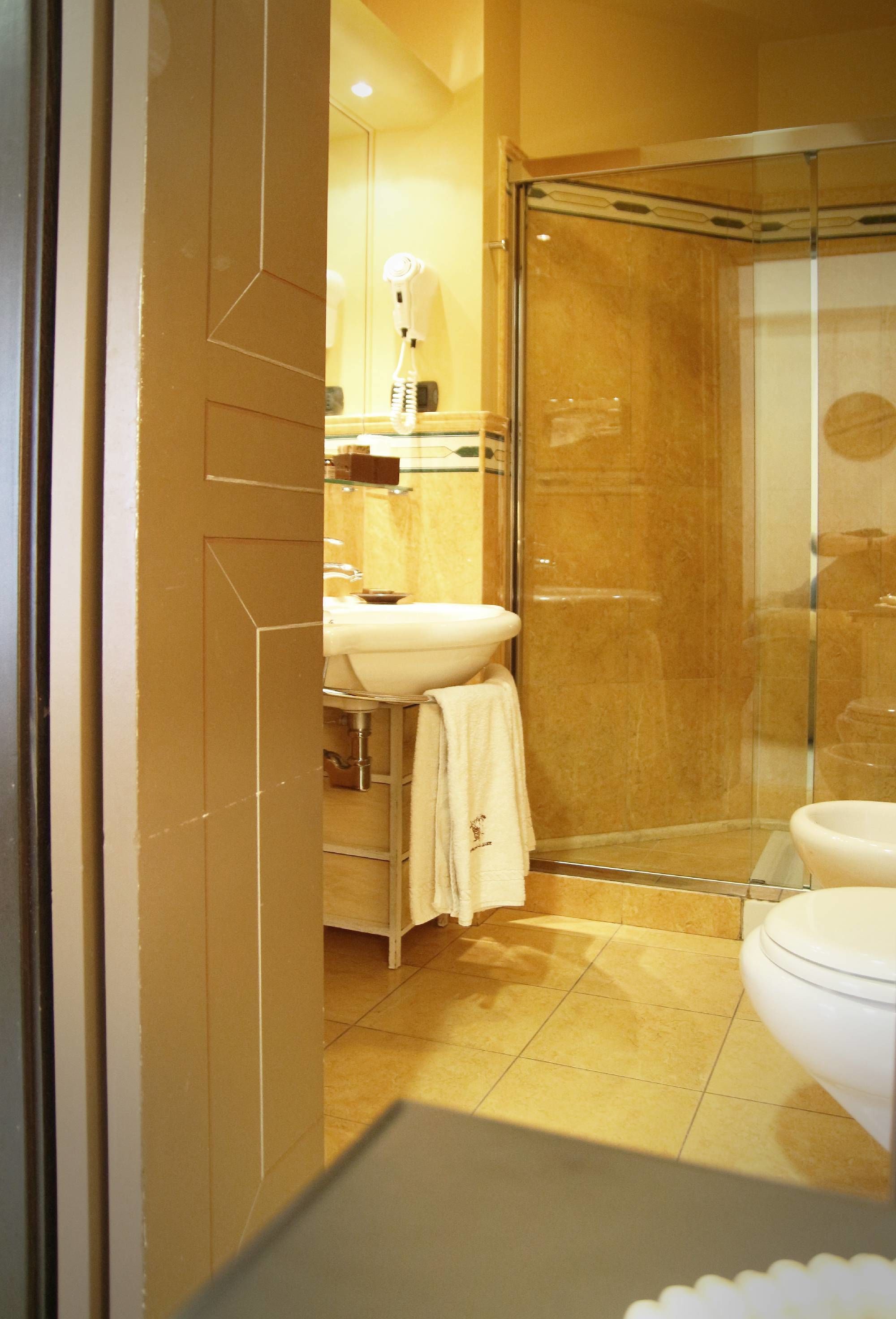 A bathroom with a glass shower enclosure, a white sink, and a toilet.