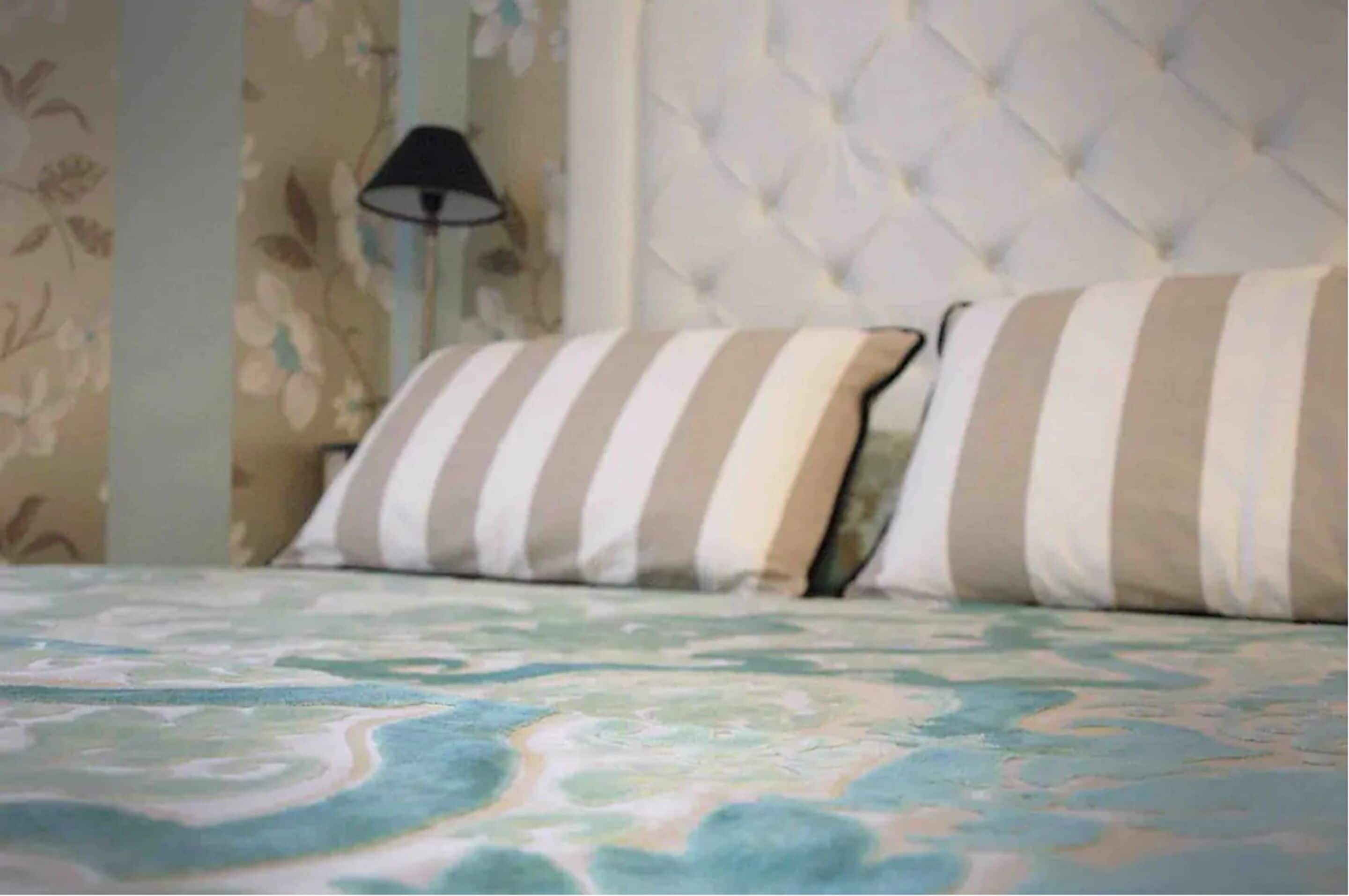 Un lit avec des oreillers à rayures et une couvre-lit à motifs floraux.