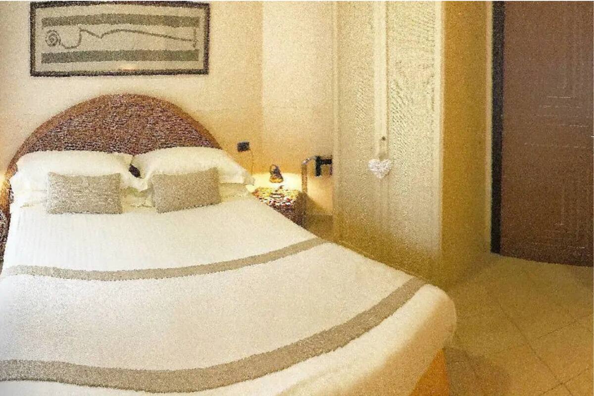 A bed with a striped blanket, a headboard, and a bedside table with a lamp.