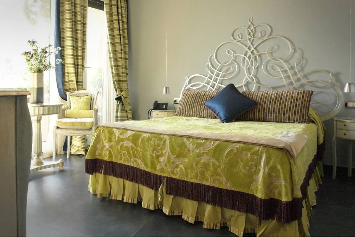 A neatly arranged bedroom with a large bed, a bedside table, a chair, and a nightstand.