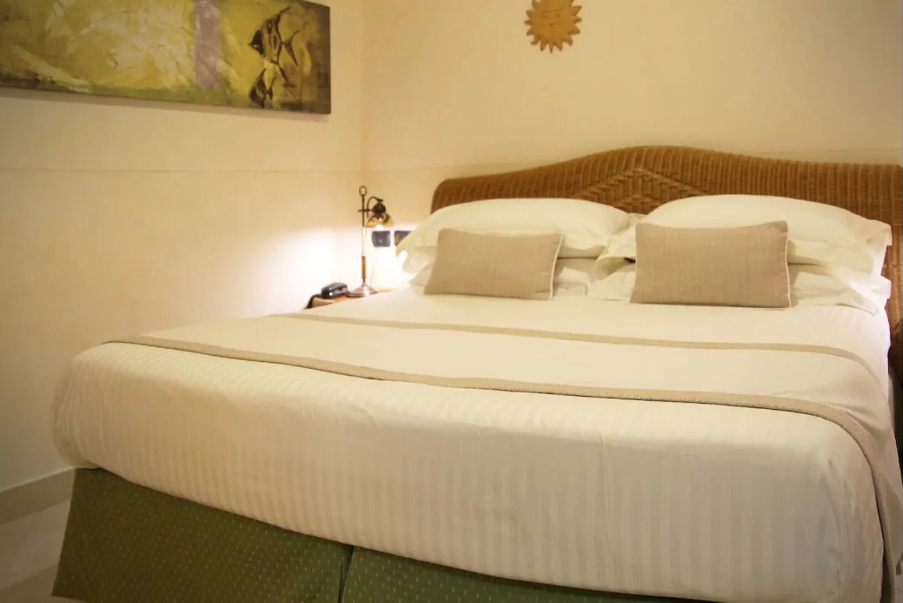 A neatly made bed with a green upholstered headboard and a beige blanket.