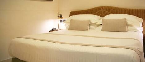 A neatly made bed with a green upholstered headboard and a beige blanket.