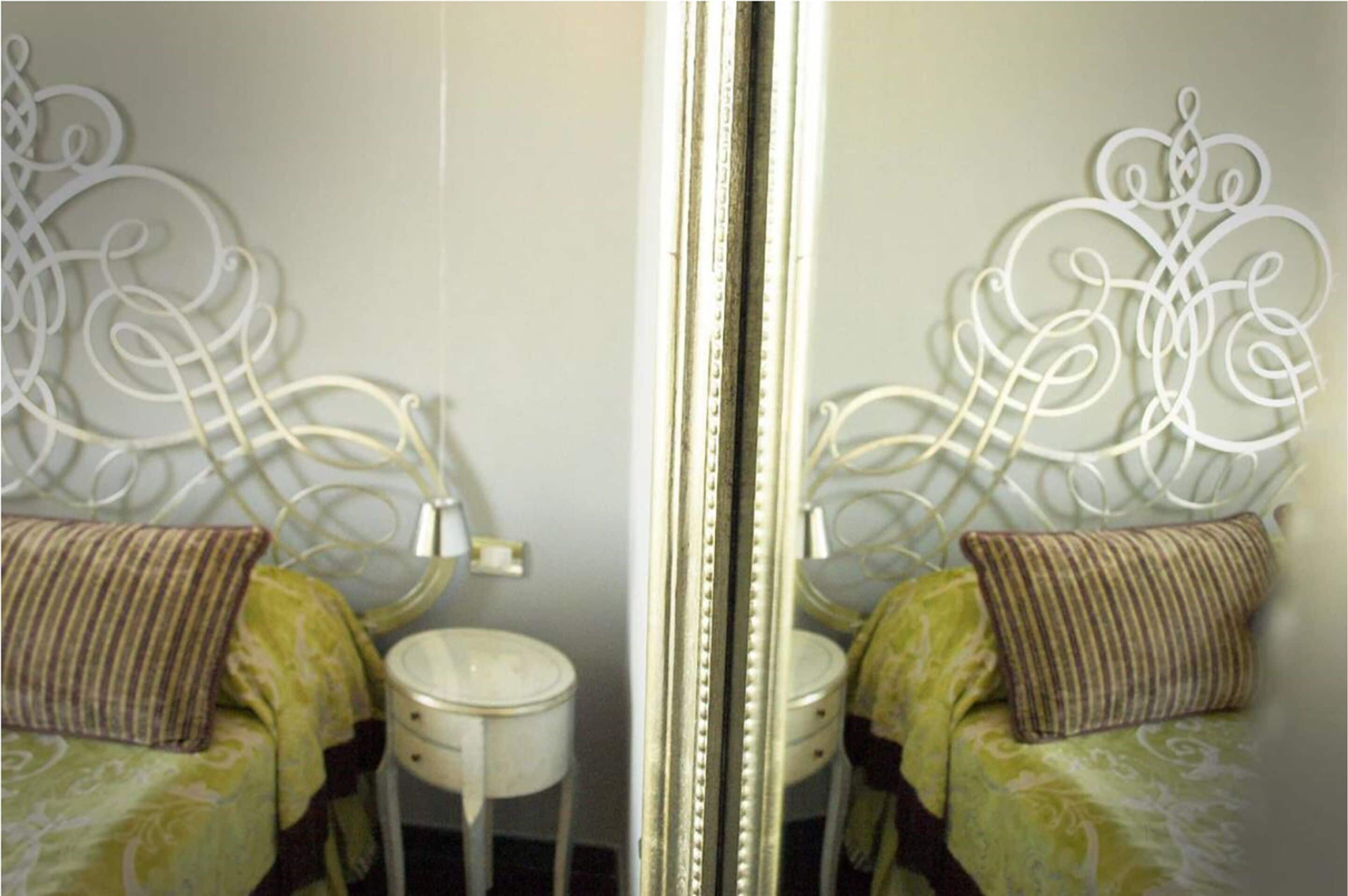 Une chambre à coucher avec un lit, une table de chevet et un miroir.