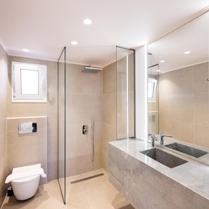 Un baño moderno con ducha de vidrio, un tocador espacioso con lavabo e inodoro.