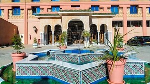 Un hotel con un patio central que cuenta con una fuente y piscina con azulejos.