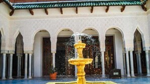 Un patio con una fuente central, rodeado de arcos y columnas.