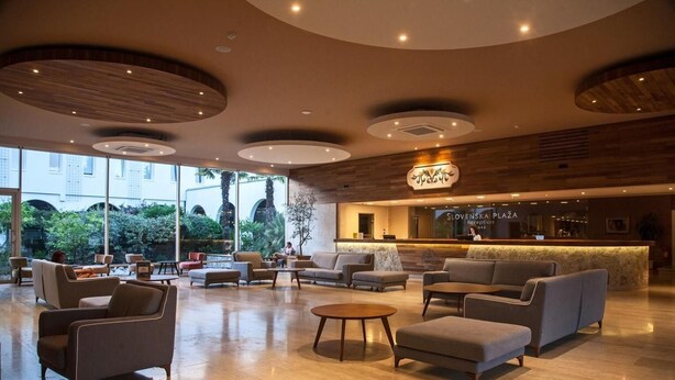 A spacious lobby with a reception desk, seating area, and large windows offering a view of the outdoors. - Slovenska Plaza Resort 4 (Budva)
