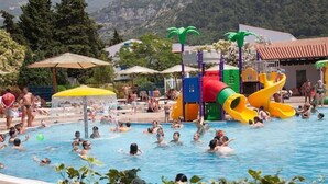 A swimming pool with people, a water slide, and palm trees. - Slovenska Plaza Resort 4 (Budva)