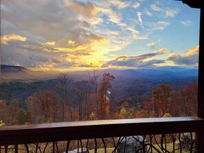 Een prachtig uitzicht vanaf een balkon met een balustrade, uitkijkend over een bergachtig landschap met herfstkleuren.