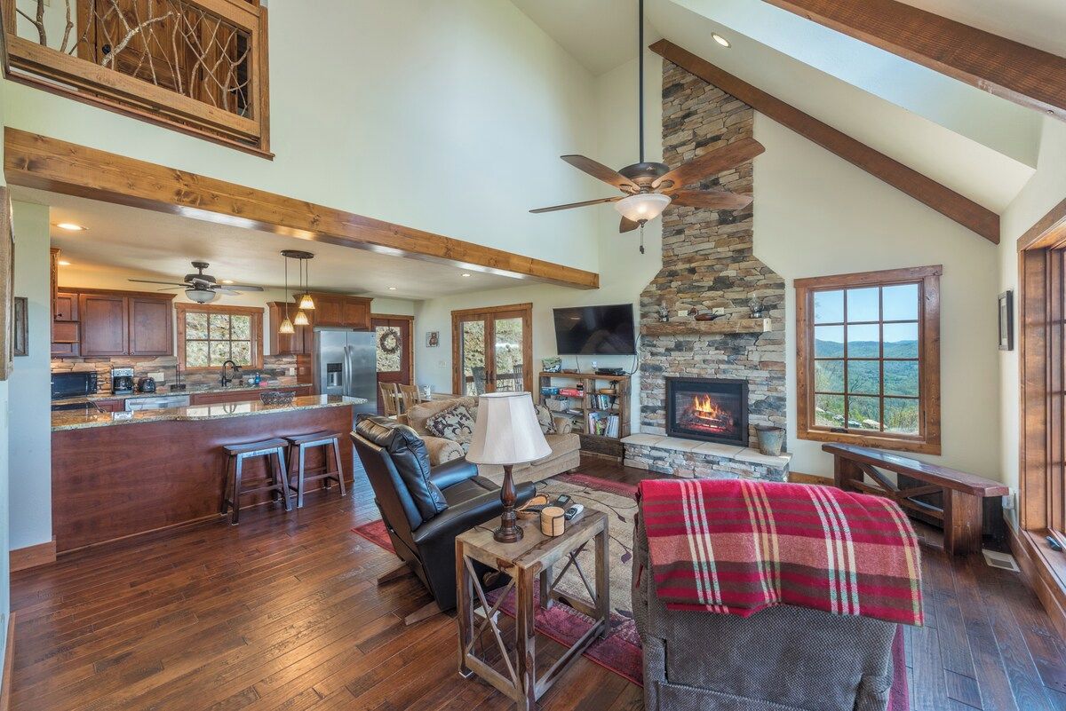 A spacious living area with a fireplace, wooden beams, and a stone accent wall.