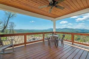 A wooden deck with a table and chairs, overlooking a mountainous landscape. - Among the Peaks | Spectacular Mtn Views+Fire Pit (Bakersville)
