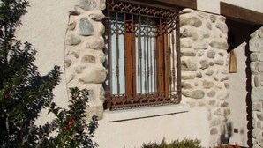 Un edificio con fachada de piedra, una ventana con barrotes y un pequeño balcón.