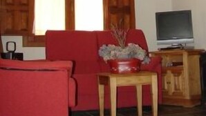 Una sala de estar con un sofá rojo, un mueble de televisión de madera y una chimenea con adornos.