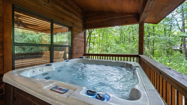 Ein Whirlpool in einer Holzhütte mit Blick auf einen Wald.