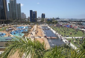 Un vaste espace extérieur doté d’une grande piscine et de plusieurs autres bassins, ainsi que d’un élément aquatique central, le tout entouré d’immeubles imposants.