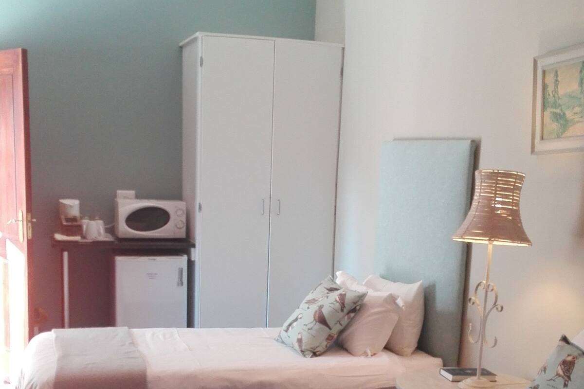 Un dormitorio con dos camas, un armario, una lámpara y un cuadro en la pared.
