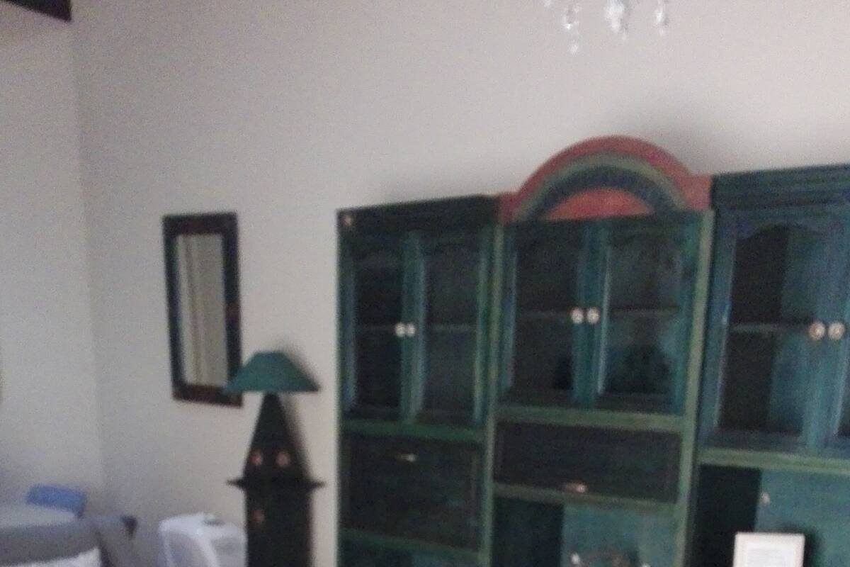 Una sala de estar con sofá, sillón, mesa de centro y aparador.