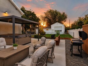 Un patio al aire libre con una parrilla, asientos y una zona cubierta.