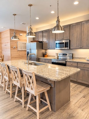 A modern kitchen with a central island, stainless steel appliances, and wooden cabinetry.