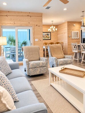 A modern living room with a sofa, two armchairs, a coffee table, and a dining area with a table and chairs.