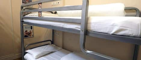 A bunk bed room with three levels, a poster on the wall, and a sign with a number.