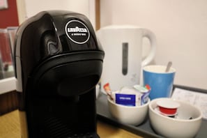 A coffee machine with a label, a white mug, and a blue mug on a tray.