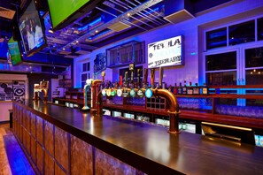 A bar with multiple taps, a counter, and a sign that reads "TEQUILA CHEAPEN".