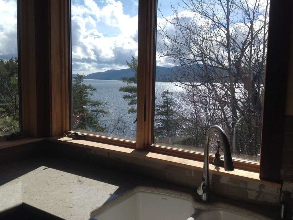 Une cuisine dotée d’une grande fenêtre donnant sur un lac et des montagnes.