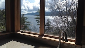A kitchen with a large window overlooking a lake and mountains.