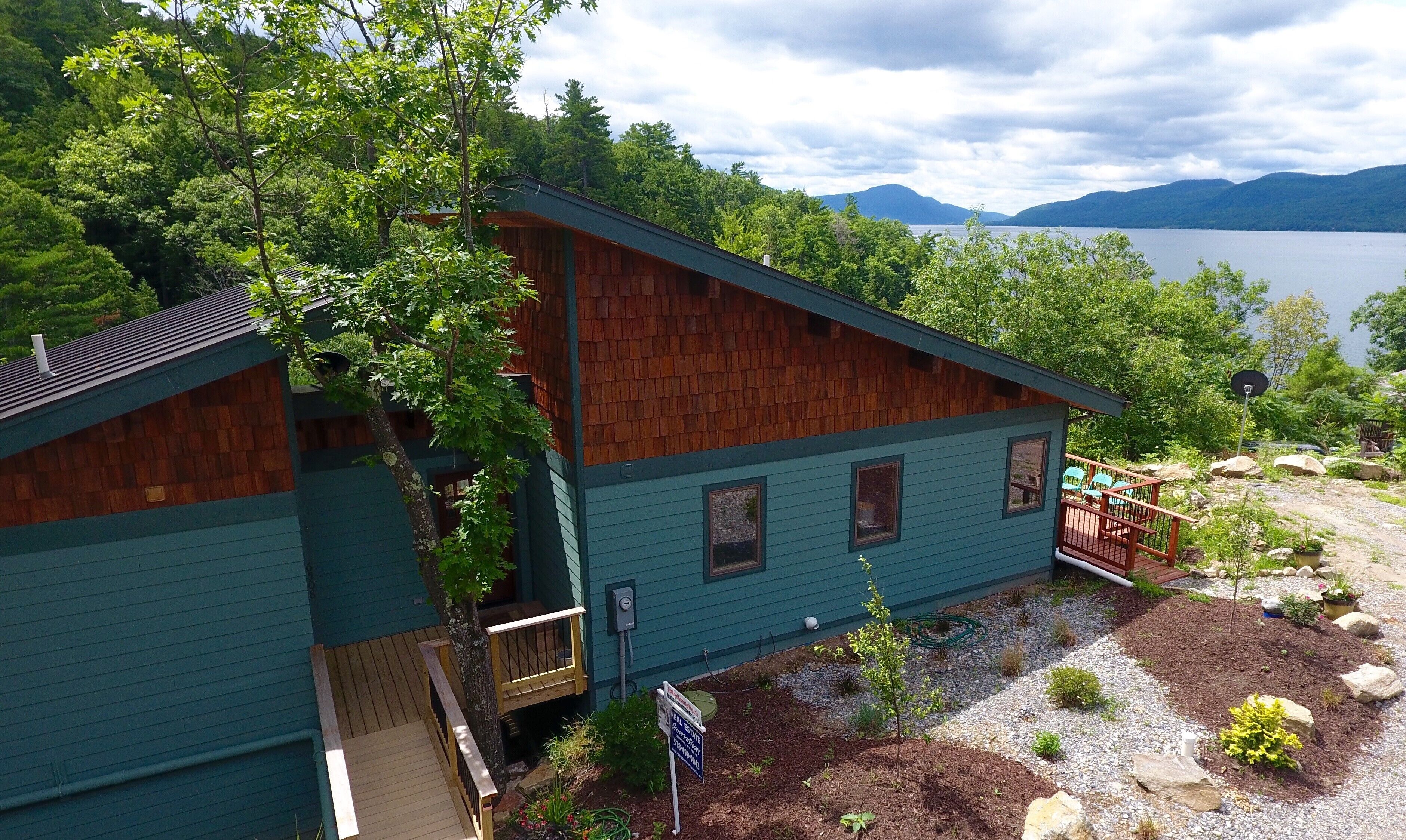 A cabin with a deck and a view of a lake and mountains.
