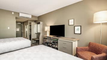 A hotel room with two beds, a desk with a computer, a television, and a chair.