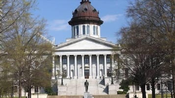 A stately building with a central dome and columns, surrounded by a well-maintained lawn and trees.