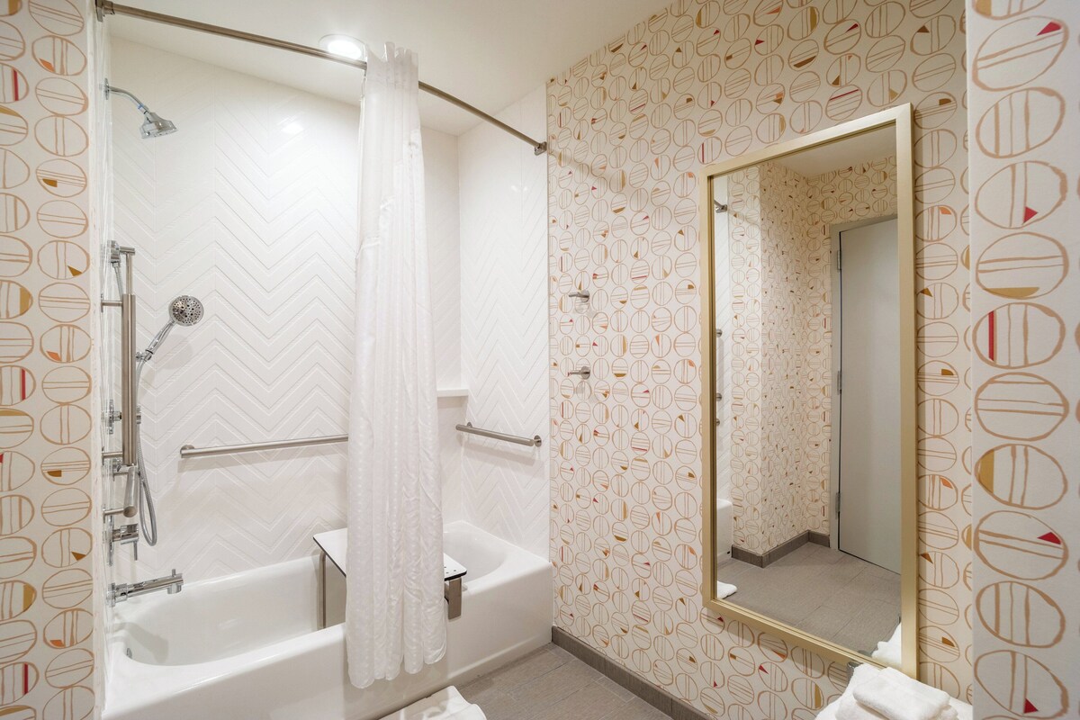 A bathroom with a bathtub, a shower, and a mirror.