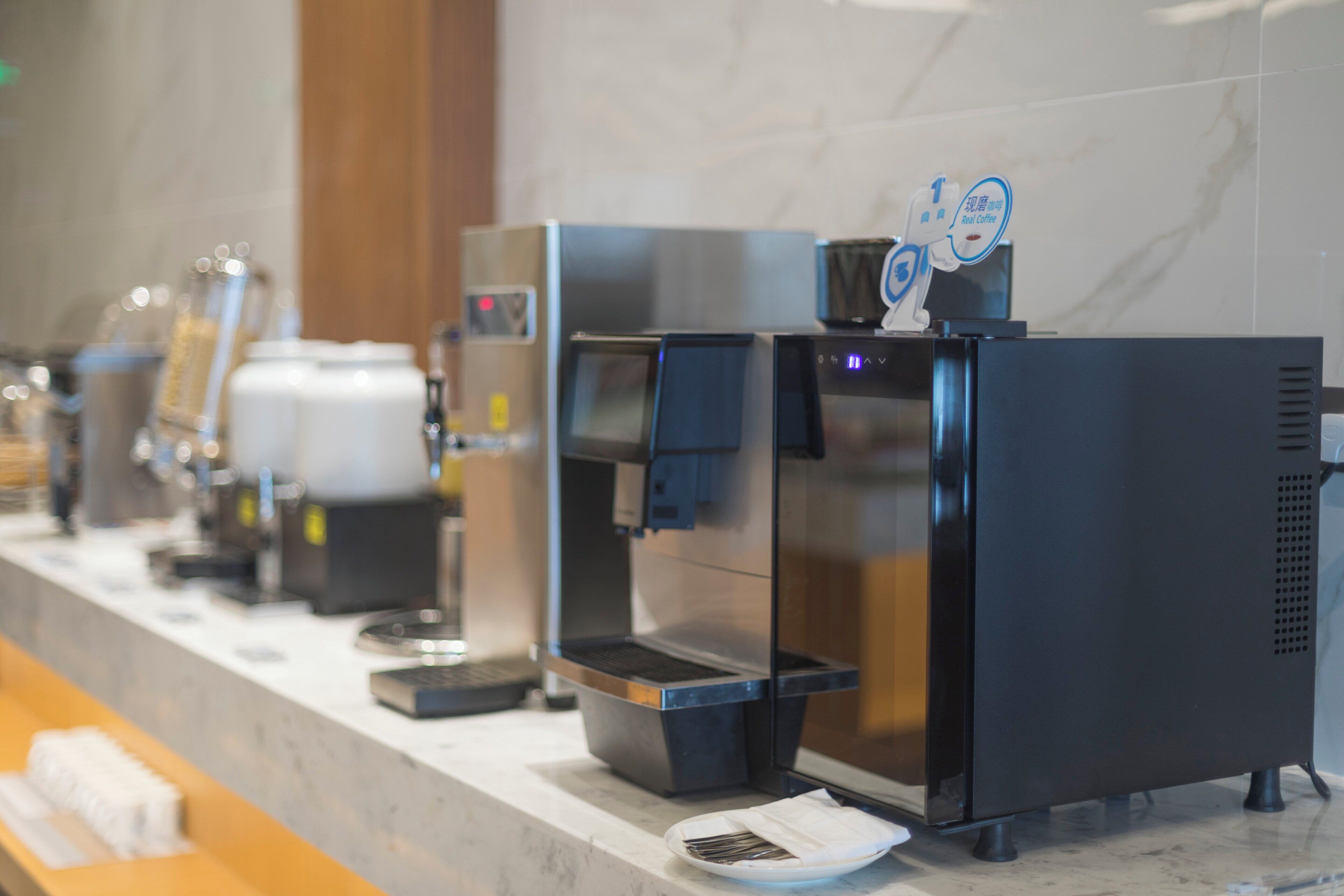 A row of coffee machines on a counter with a marble backsplash.
