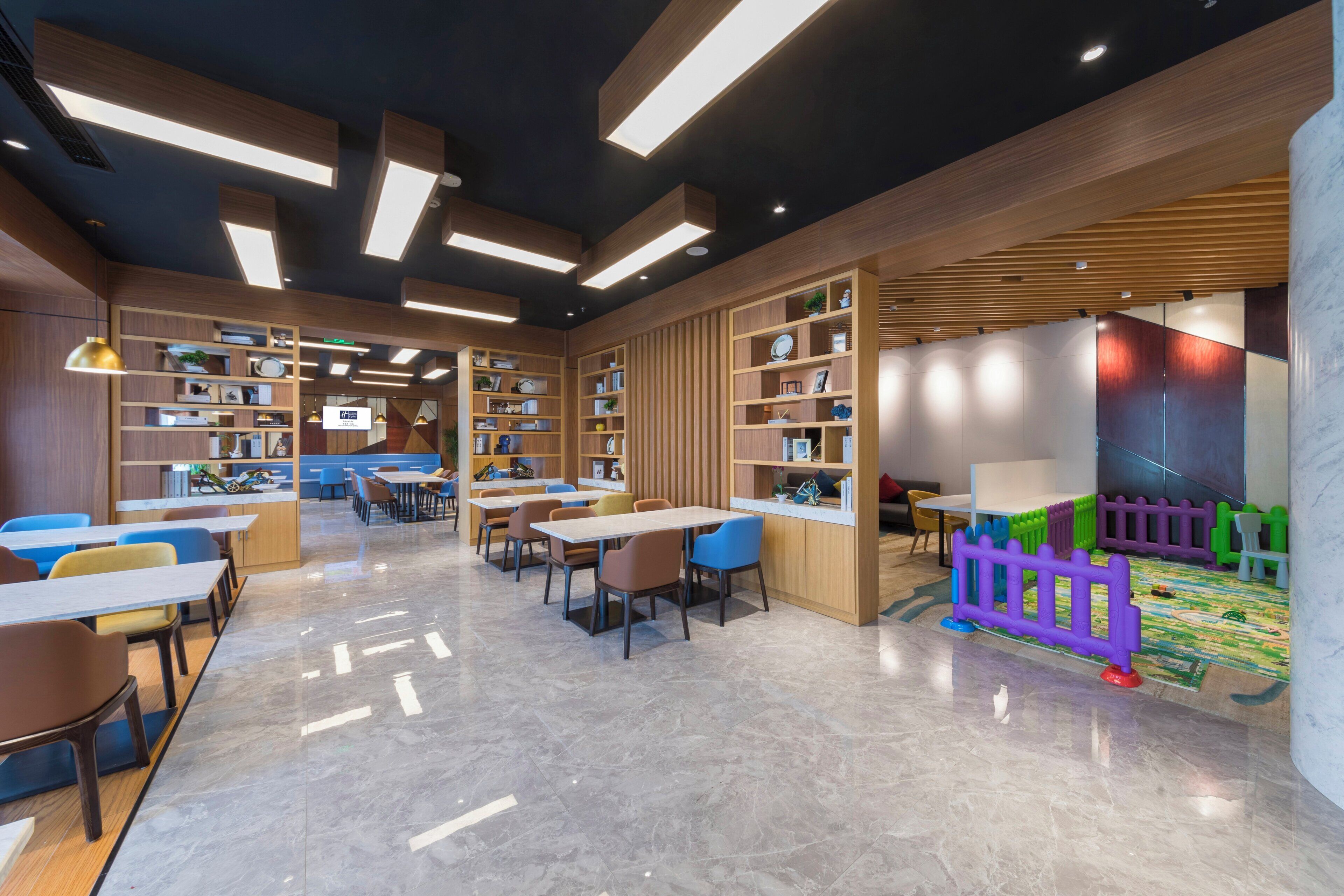 Una biblioteca moderna con estanterías, mesas, sillas y una zona de juegos para niños.