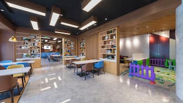 Una biblioteca moderna con estanterías, mesas, sillas y una zona de juegos para niños.