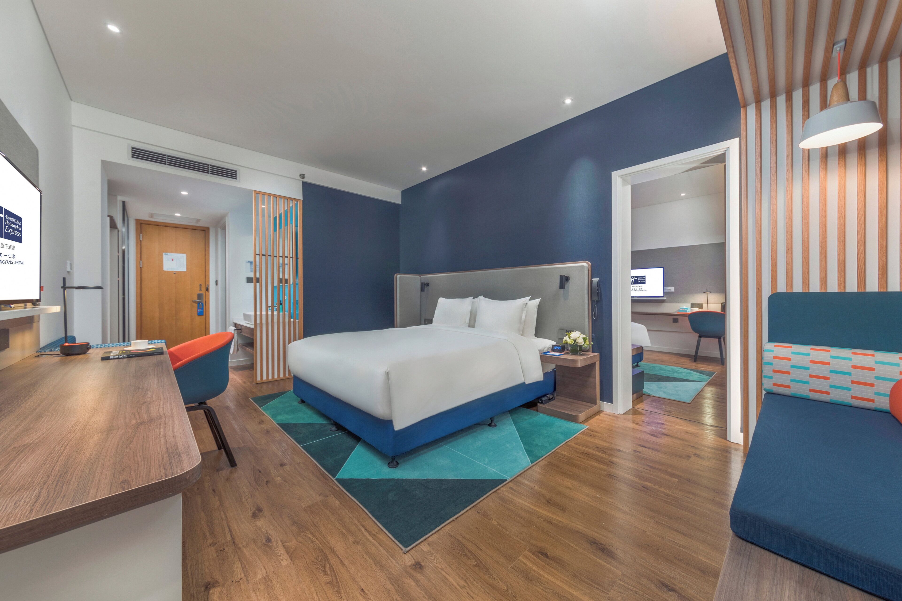Una camera d'albergo moderna con un letto grande, una scrivania e un angolo salotto.