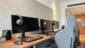 A modern office setup with three monitors, a keyboard, a mouse, and headphones on each desk.