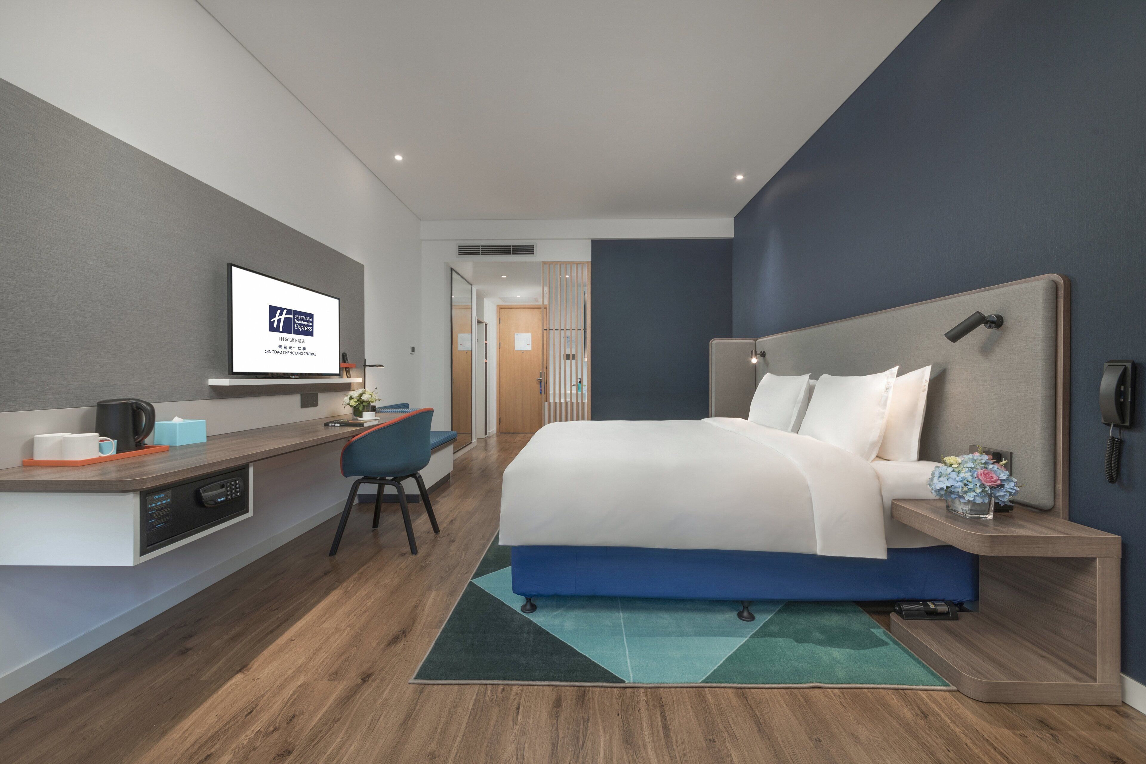 Una camera d'albergo moderna con un letto grande, una scrivania con un computer e un televisore a parete.
