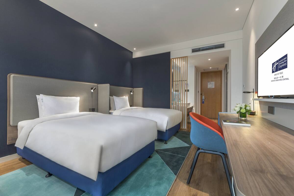 Ein Hotelzimmer mit zwei Betten, einem Schreibtisch und einem Stuhl.