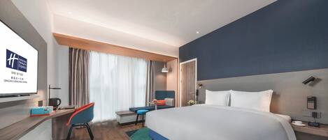 A modern hotel room with a large bed, a desk, a chair, and a television.