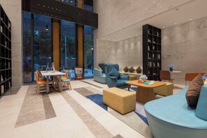 A modern lounge area with a marble floor, seating arrangements, and a large window offering a view of the outdoors. - Holiday Inn Express Qingdao Chengyang Central by IHG (Qingdao)