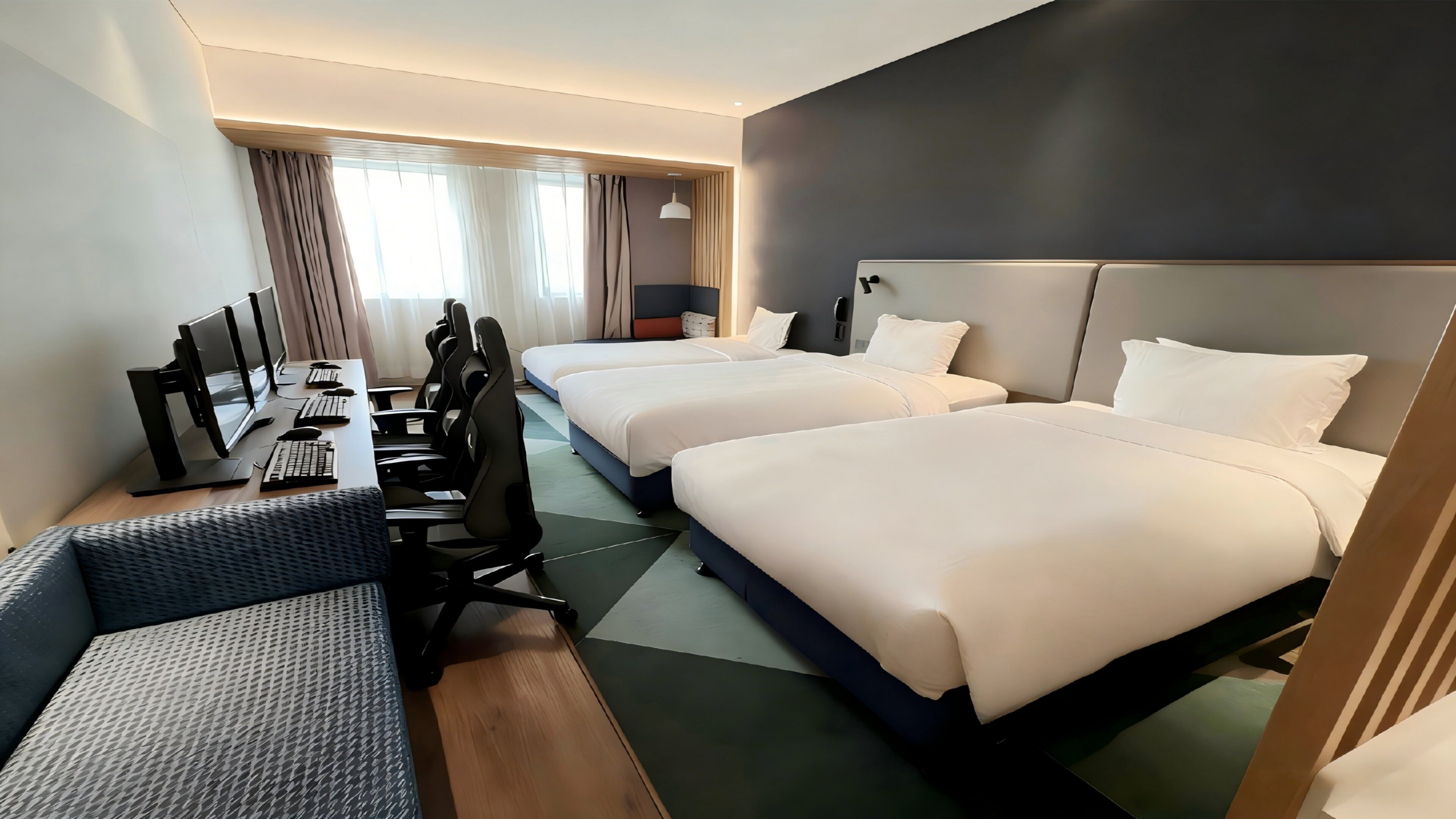 A hotel room with two beds, a desk with a computer, and a chair.