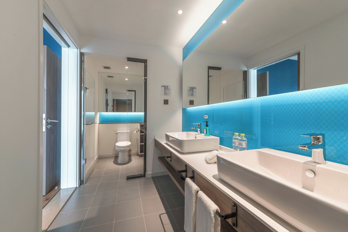 A modern bathroom with a dual sink vanity, a toilet, and a shower area.