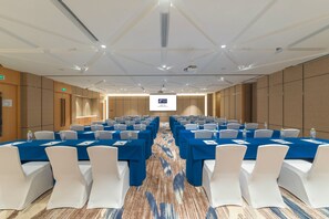 A conference room with rows of tables and chairs, a projector screen, and a carpeted floor. - Holiday Inn Express Qingdao Chengyang Central by IHG (Qingdao)