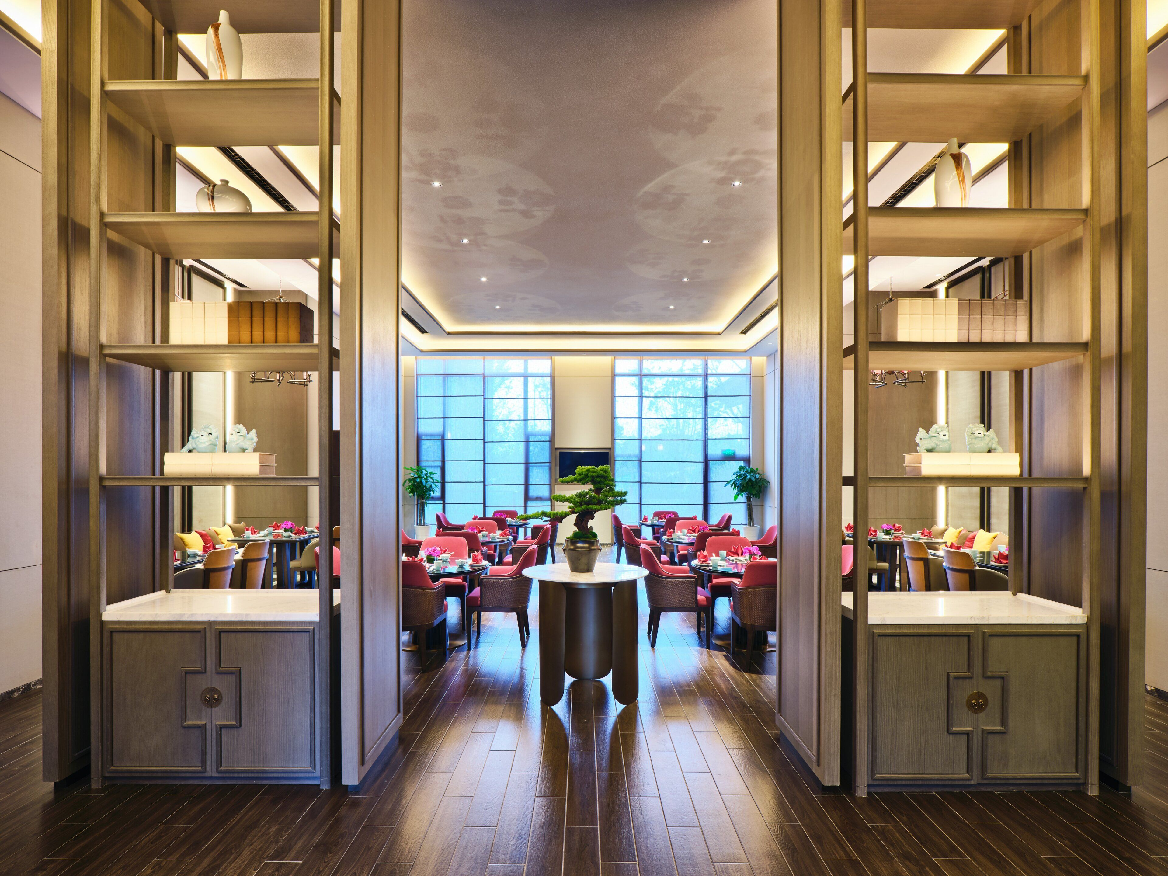 Eine geräumige Hotellobby mit einem runden Tisch in der Mitte, Sitzgelegenheiten und einem großen Fenster, das natürliches Licht hereinlässt.