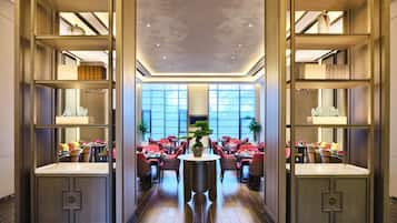 Eine geräumige Hotellobby mit einem runden Tisch in der Mitte, Sitzgelegenheiten und einem großen Fenster, das natürliches Licht hereinlässt.