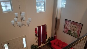 A spacious living area with a red sofa, a chandelier, and a painting on the wall. - Spacious 5 Bedroom rental (Waukesha)