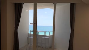 A hotel room with a bed, a balcony with a table and chairs, and a view of the sea. - Oceanfront Studio w/balcony & Private Beach - Walk to shops & Dining (Fort Lauderdale)