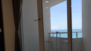 A room with a bed, a sliding glass door leading to a balcony with a view of the sea. - Oceanfront Studio w/balcony & Private Beach - Walk to shops & Dining (Fort Lauderdale)